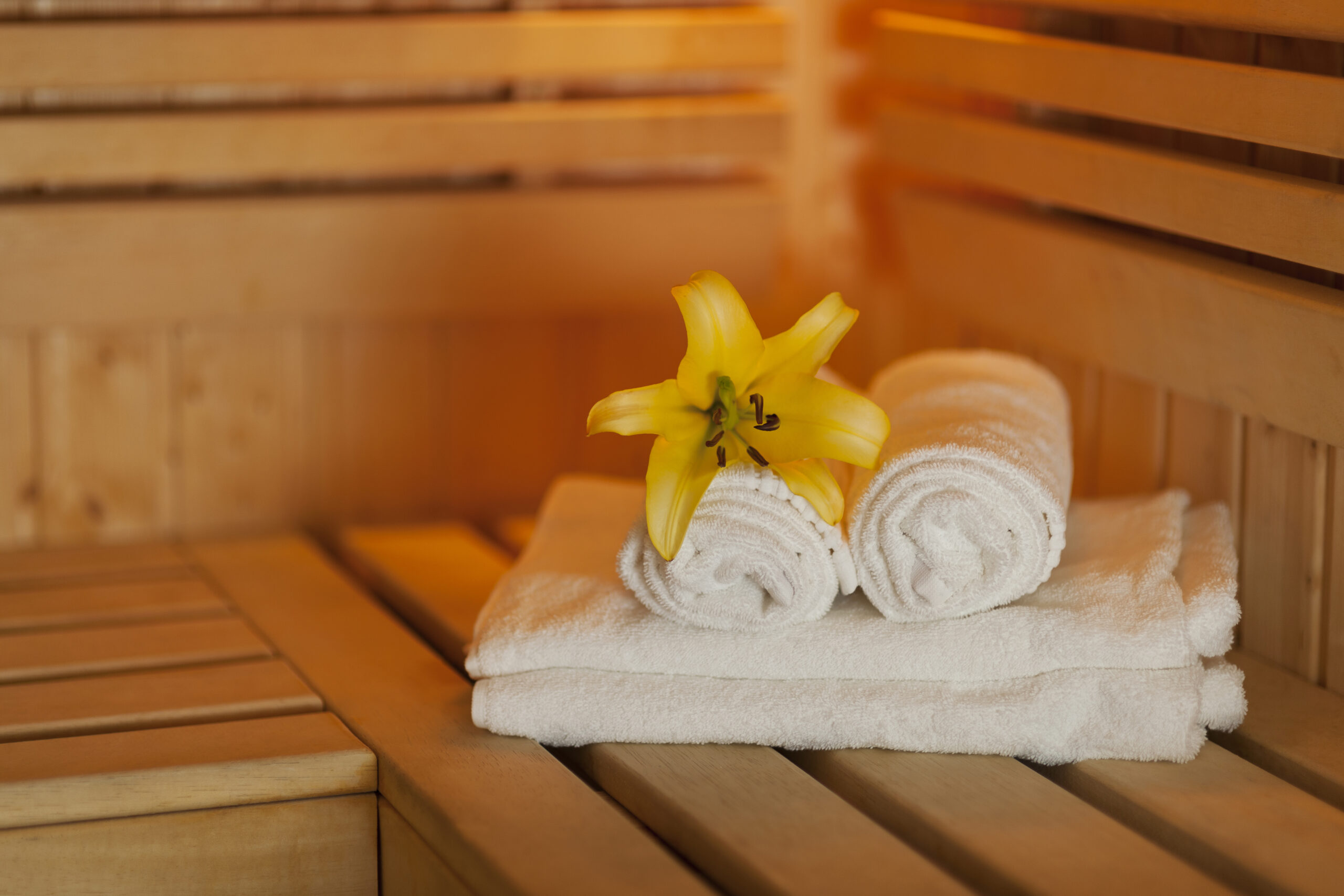 Close up fresh towels and yellow lily in sauna